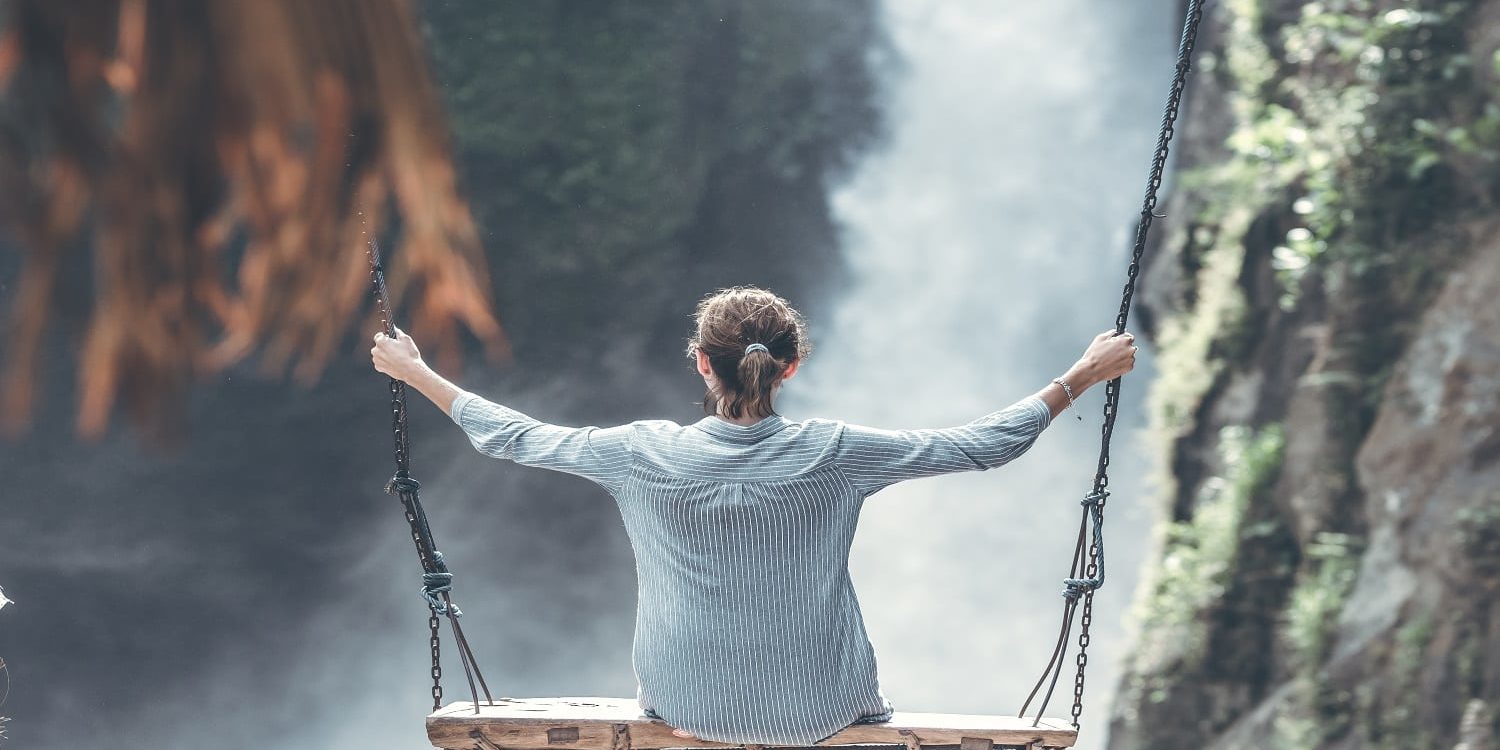 Beautiful woman swings near waterfall in the jungle of Bali island.
