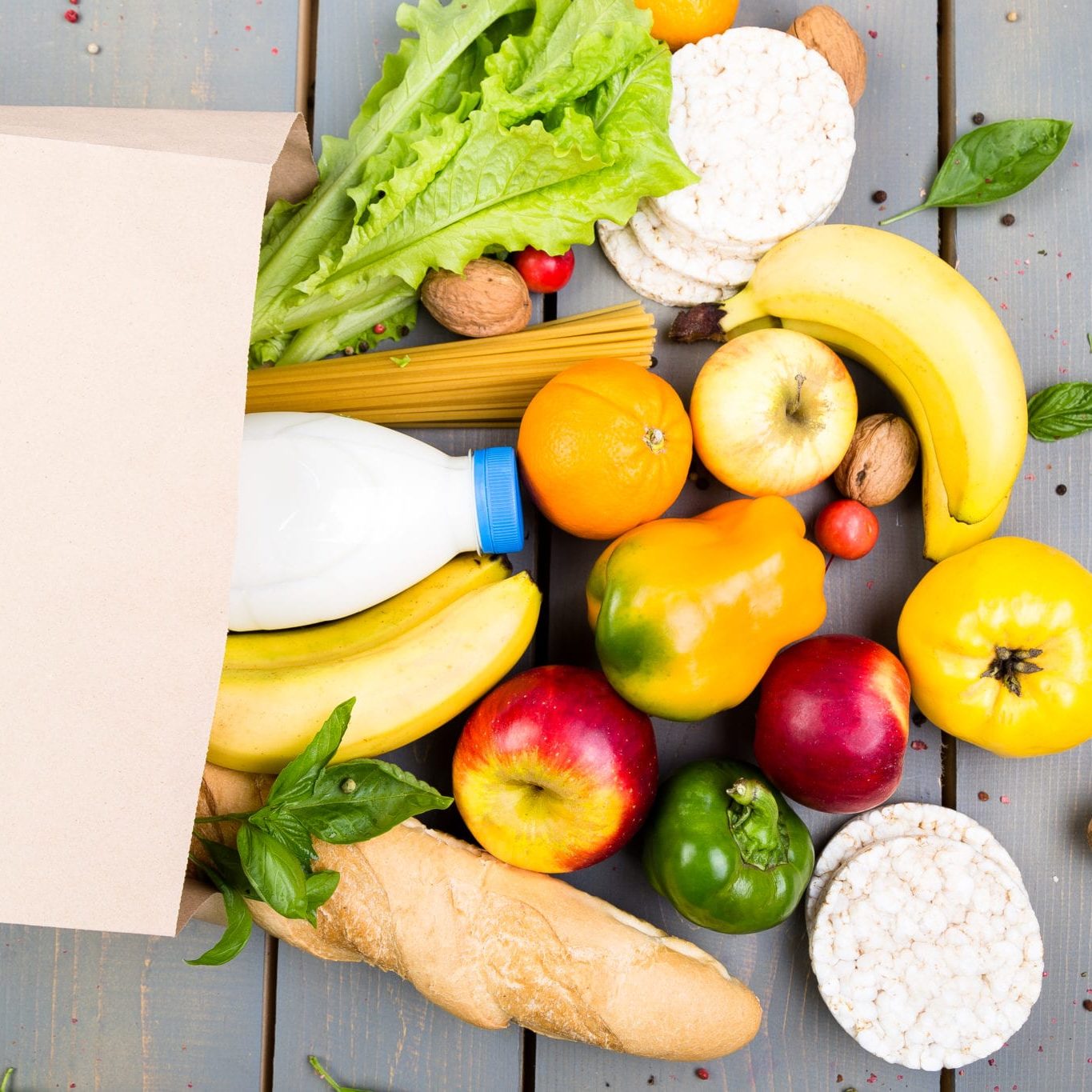 Grocery shopping concept. Different food in paper bag on wooden background.  Flat lay